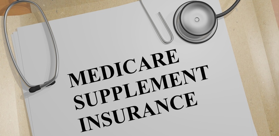 A Medicare Supplement Insurance policy is laying on a table with a stethoscope on top of it.